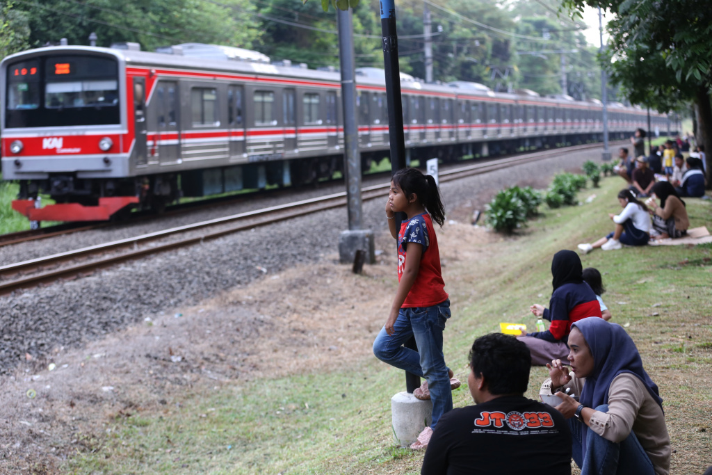 Warga sedang menunggu senja disamping rel kereta tanah kusir (Ashar/SinPo.id)