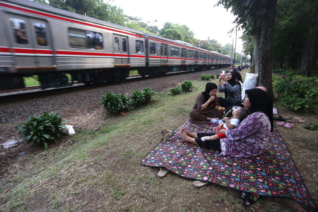 Warga sedang menunggu senja disamping rel kereta tanah kusir (Ashar/SinPo.id)