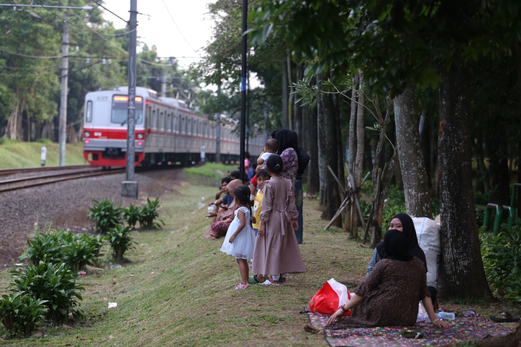 Warga sedang menunggu senja disamping rel kereta tanah kusir (Ashar/SinPo.id)