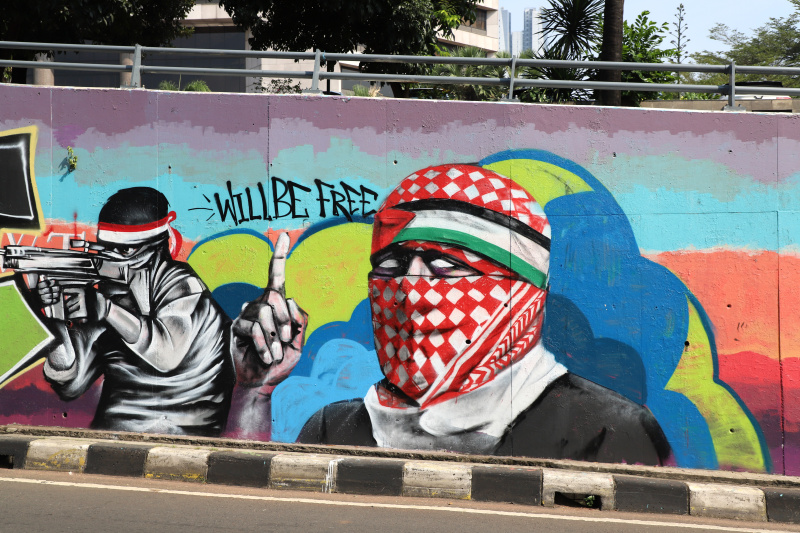 Mural dukungan solidaritas bela Palestina dengan gambar Perdana Menteri Israel Benyamin Natayanhu Stop Genocide di Sudirman (Ashar/SinPo.id)