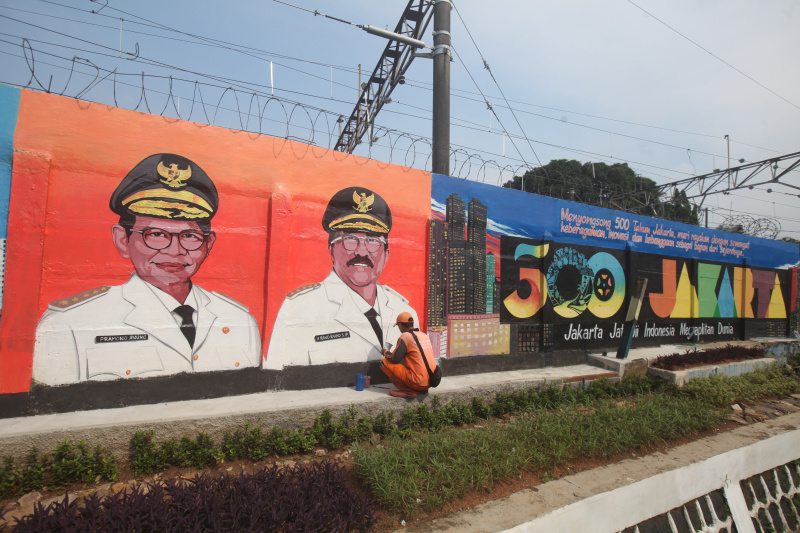 Pasukan Orange sedang mengerjakan mural wajah Gubernur DKI Jakarta dan Sambut HUT ke-500 tahun Kota Jakarta di Bukit Duri