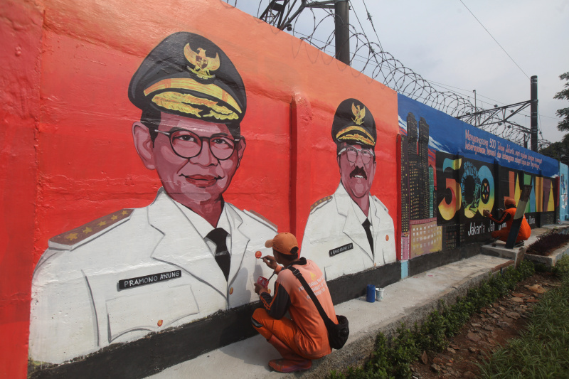 Pasukan Orange sedang mengerjakan mural wajah Gubernur DKI Jakarta dan Sambut HUT ke-500 tahun Kota Jakarta di Bukit Duri