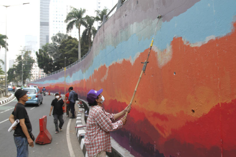 Jakarta Mural Community memgecat tembok di depan gedung BNI untuk menyambut pergelaran dunia KTT ASEAN (Ashar/SinPo.id)