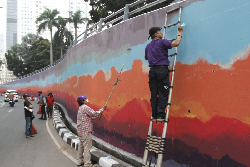 Jakarta Mural Community memgecat tembok di depan gedung BNI untuk menyambut pergelaran dunia KTT ASEAN (Ashar/SinPo.id)