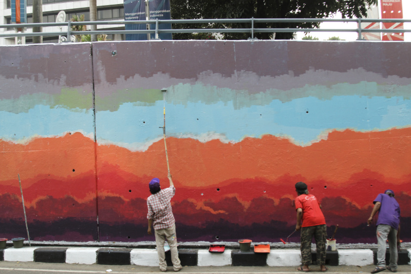 Jakarta Mural Community memgecat tembok di depan gedung BNI untuk menyambut pergelaran dunia KTT ASEAN (Ashar/SinPo.id)