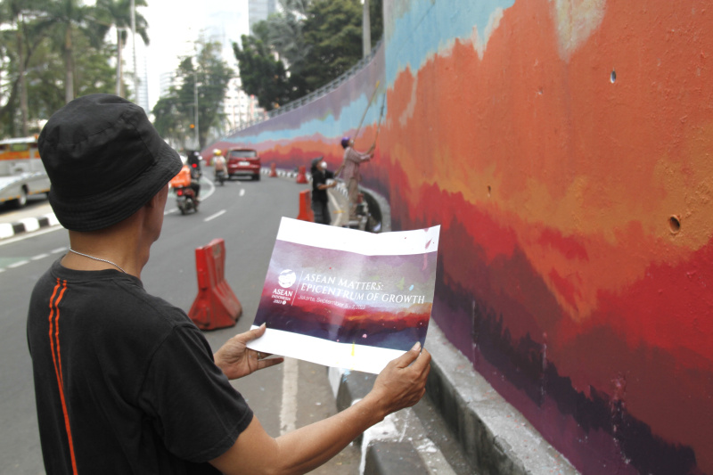 Jakarta Mural Community memgecat tembok di depan gedung BNI untuk menyambut pergelaran dunia KTT ASEAN (Ashar/SinPo.id)