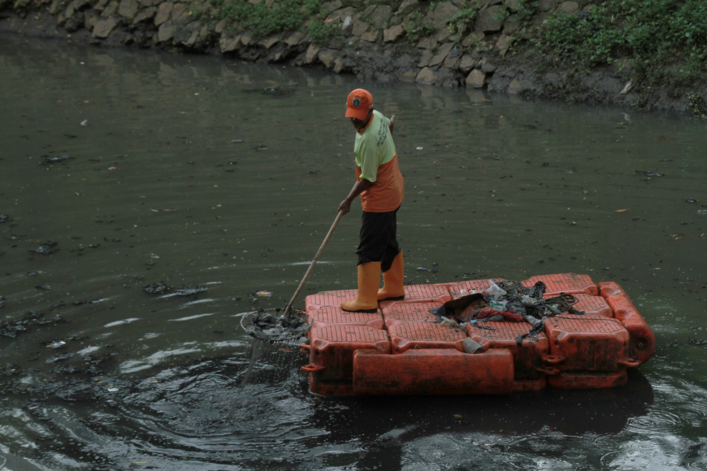Pekerja Dinas Badan Air Lingkungan Hidup sedang membersihkan sampah dan lumpur di sungai kuningan (Ashar/SinPo.id)