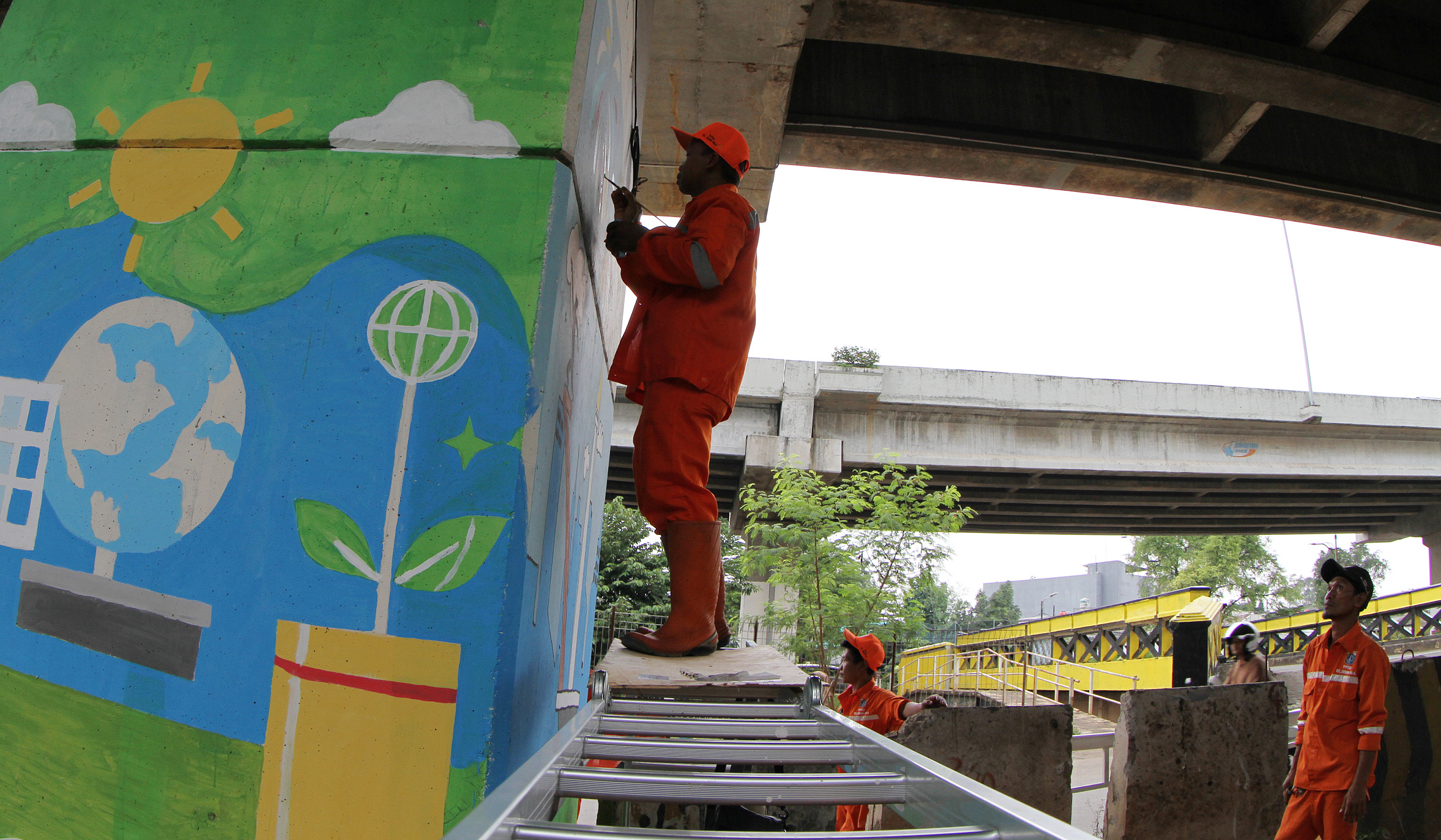 Pasukan oranye mengecat mural dikolong tol Becakayu. (Agus Priatna/SinPo.id)