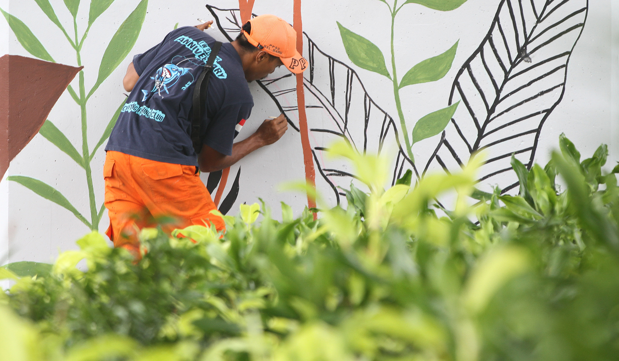 Pasukan oranye mengecat mural dikolong tol Becakayu. (Agus Priatna/SinPo.id)