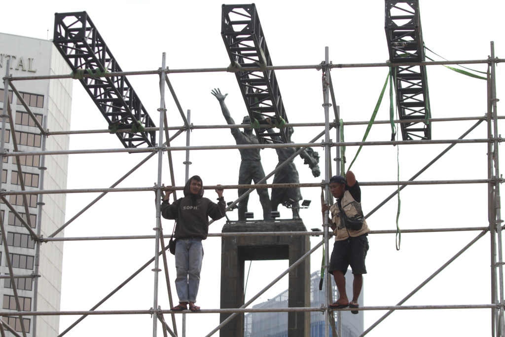 Para pekerja sedang menyelesaikan pembuatan panggung untuk penyambutan perayaan malam tahun baru (Ashar/SinPo.id)