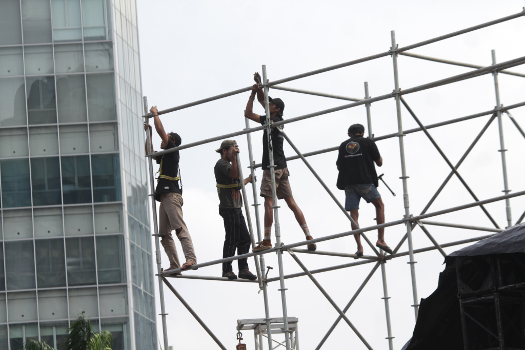 Para pekerja sedang menyelesaikan pembuatan panggung untuk penyambutan perayaan malam tahun baru (Ashar/SinPo.id)