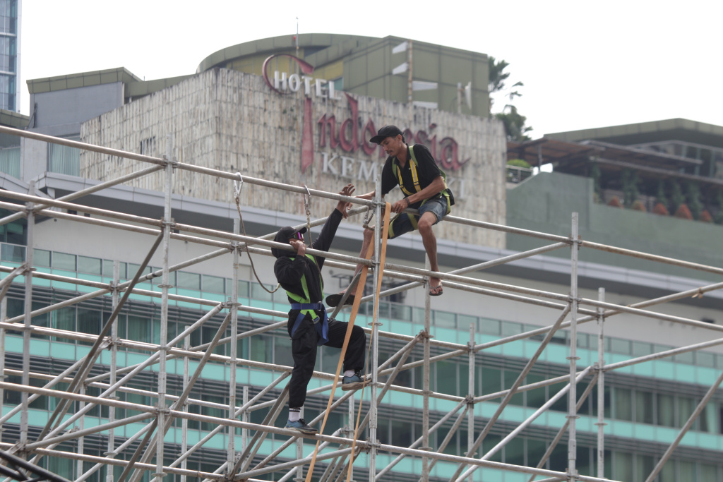 Para pekerja sedang menyelesaikan pembuatan panggung untuk penyambutan perayaan malam tahun baru (Ashar/SinPo.id)