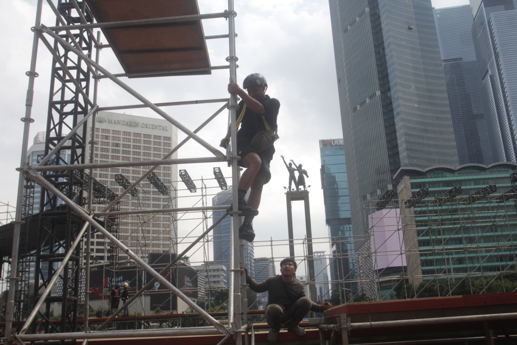 Para pekerja sedang menyelesaikan pembuatan panggung untuk penyambutan perayaan malam tahun baru (Ashar/SinPo.id)