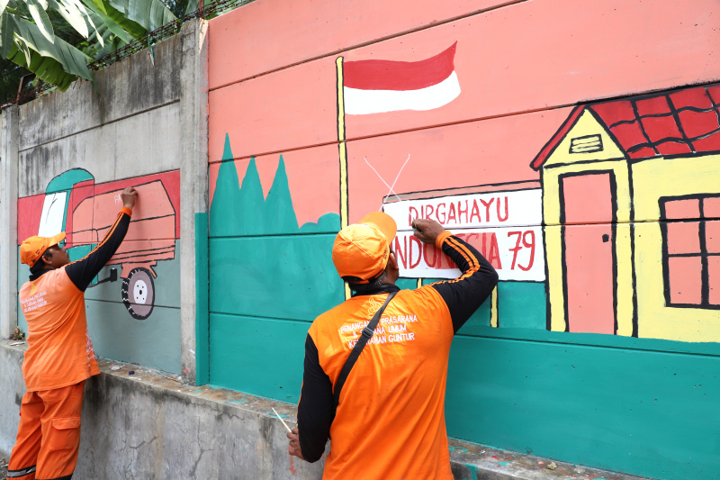 Petugas PPSU Guntur Jakarta Selatan membuat mural untuk menyambut Hari Kemerdekaan Republik Indonesia ke-79 (Ashar/SinPo.id)