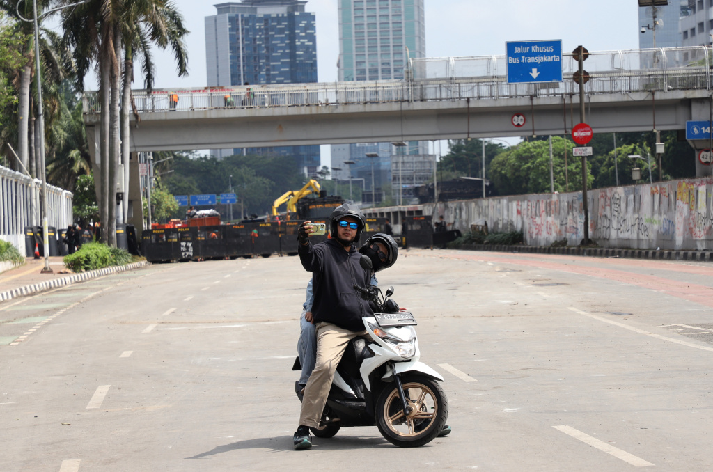 Petugas PPSU dan Dinas Bina Marga Provinsi DKI Jakarta sedang membersihkan jalan dan coretan vandalisme di tembok gedung DPR (Ashar/SinPo.id)
