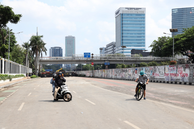 Petugas PPSU dan Dinas Bina Marga Provinsi DKI Jakarta sedang membersihkan jalan dan coretan vandalisme di tembok gedung DPR (Ashar/SinPo.id)
