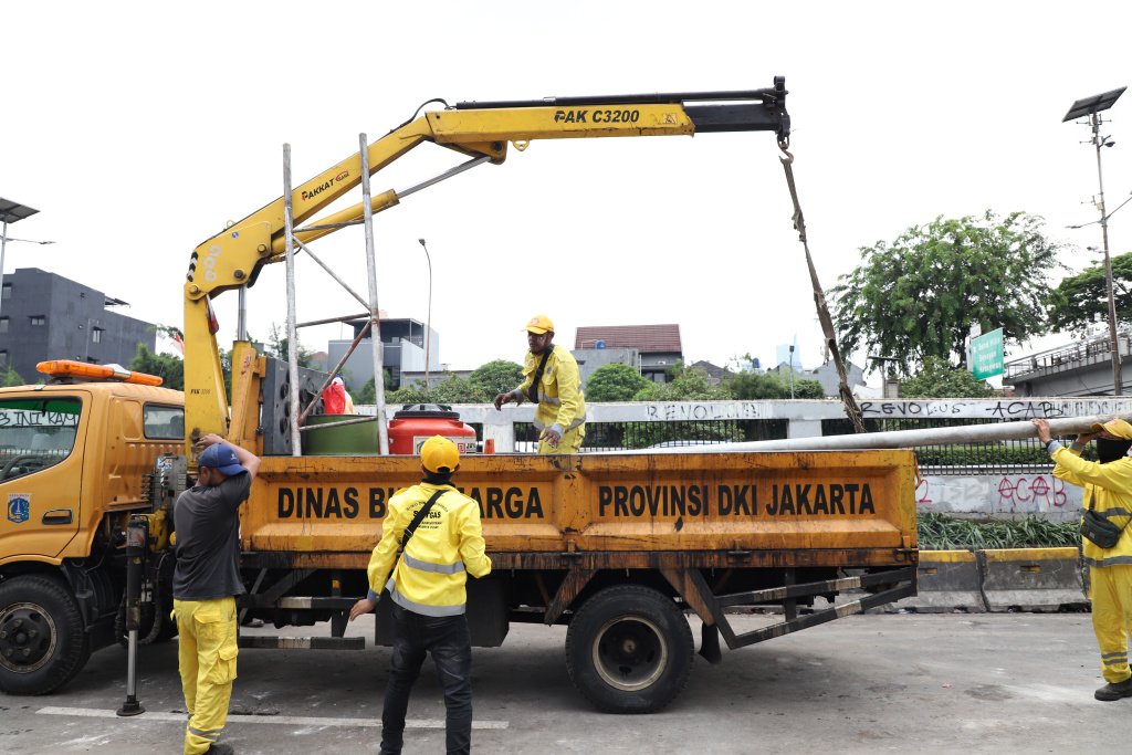 Petugas PPSU dan Dinas Bina Marga Provinsi DKI Jakarta sedang membersihkan jalan dan coretan vandalisme di tembok gedung DPR (Ashar/SinPo.id)