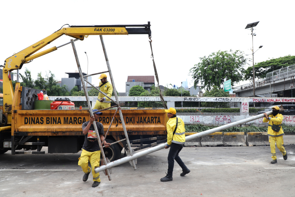 Petugas PPSU dan Dinas Bina Marga Provinsi DKI Jakarta sedang membersihkan jalan dan coretan vandalisme di tembok gedung DPR (Ashar/SinPo.id)