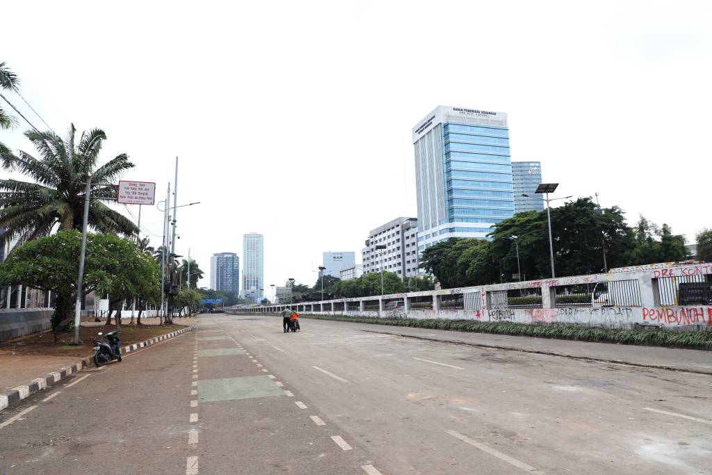 Petugas PPSU dan Dinas Bina Marga Provinsi DKI Jakarta sedang membersihkan jalan dan coretan vandalisme di tembok gedung DPR (Ashar/SinPo.id)