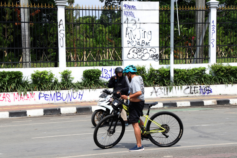 Petugas PPSU dan Dinas Bina Marga Provinsi DKI Jakarta sedang membersihkan jalan dan coretan vandalisme di tembok gedung DPR (Ashar/SinPo.id)