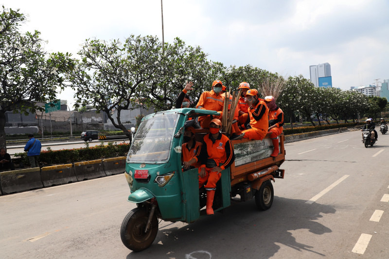 Petugas PPSU dan Dinas Bina Marga Provinsi DKI Jakarta sedang membersihkan jalan dan coretan vandalisme di tembok gedung DPR (Ashar/SinPo.id)