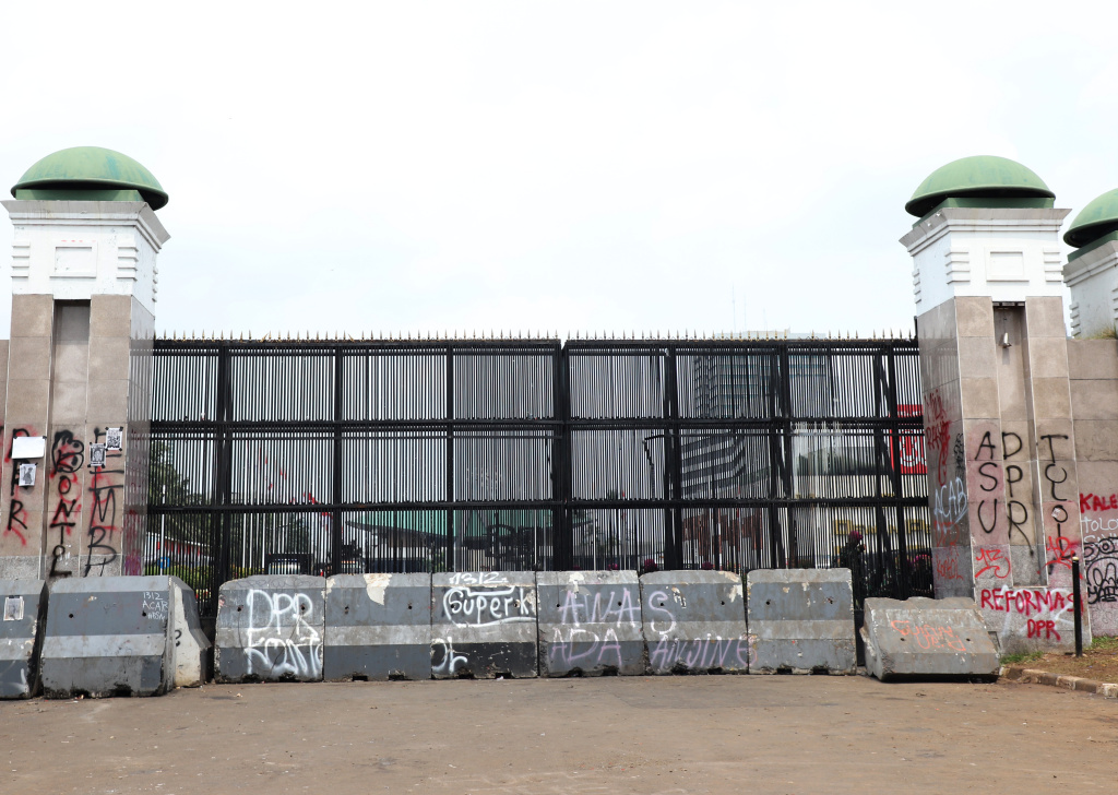 Petugas PPSU dan Dinas Bina Marga Provinsi DKI Jakarta sedang membersihkan jalan dan coretan vandalisme di tembok gedung DPR (Ashar/SinPo.id)