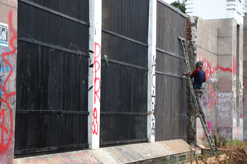 Petugas PPSU dan Dinas Bina Marga Provinsi DKI Jakarta sedang membersihkan jalan dan coretan vandalisme di tembok gedung DPR (Ashar/SinPo.id)