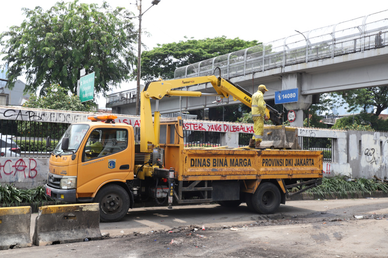 Petugas PPSU dan Dinas Bina Marga Provinsi DKI Jakarta sedang membersihkan jalan dan coretan vandalisme di tembok gedung DPR (Ashar/SinPo.id)