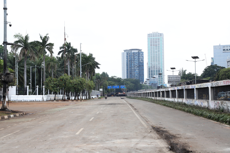 Petugas PPSU dan Dinas Bina Marga Provinsi DKI Jakarta sedang membersihkan jalan dan coretan vandalisme di tembok gedung DPR (Ashar/SinPo.id)