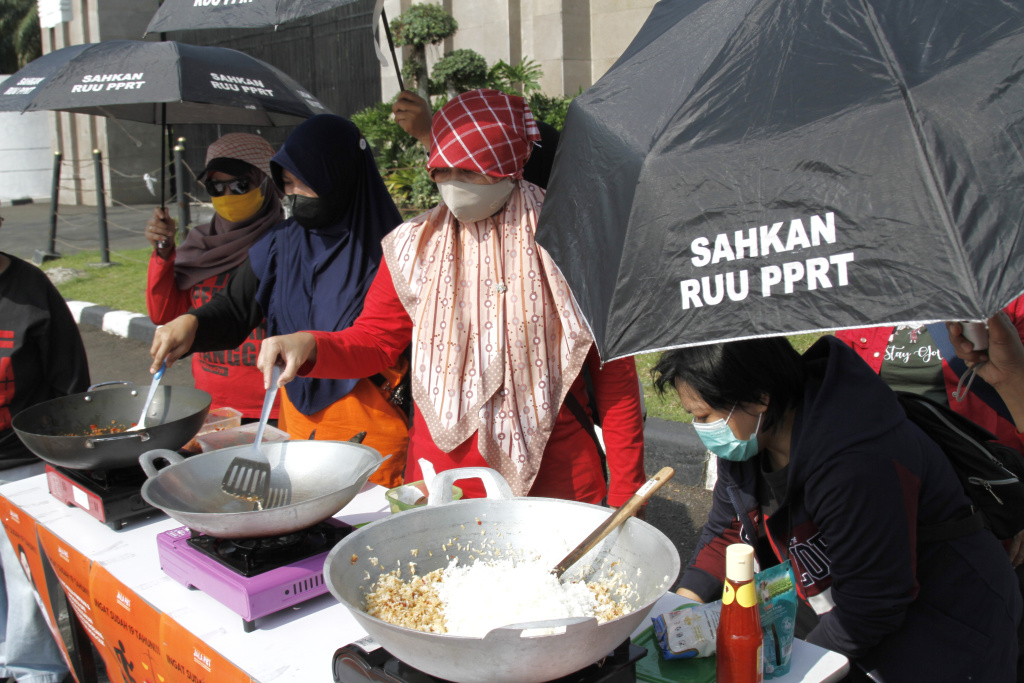 Massa dari Koalisi sipil pekerja rumah tangga  gelar demo teatrikal memasak sarapan nasi goreng di depan Gedung DPR RI (Ashar/SinPo.id)