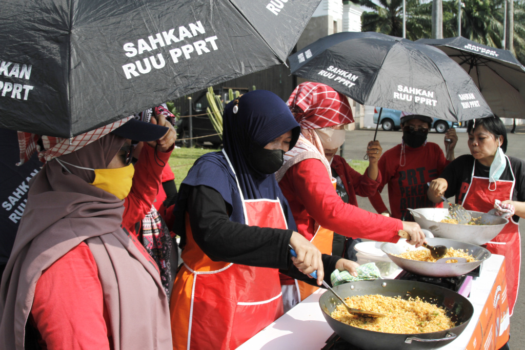 Massa dari Koalisi sipil pekerja rumah tangga  gelar demo teatrikal memasak sarapan nasi goreng di depan Gedung DPR RI (Ashar/SinPo.id)