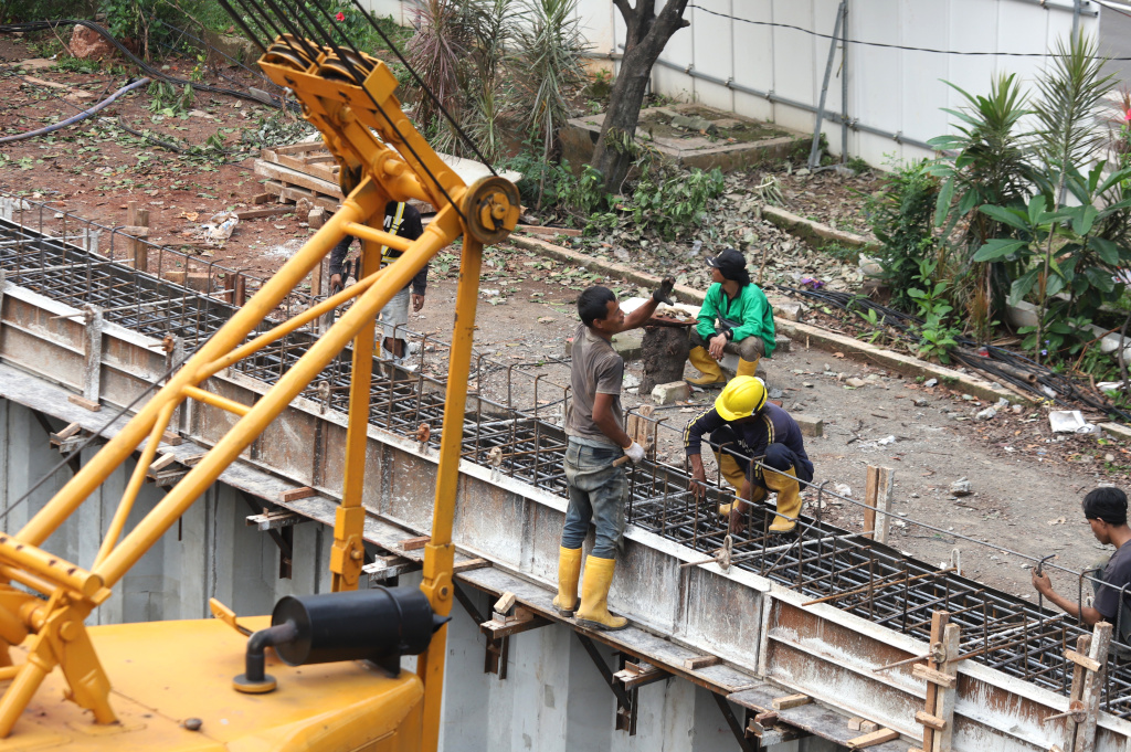 Pekerja sedang memasang rangka besi pada proyek pembangunan dinding turap Kali Cideng Atas, Jalan Rasuna Said (Ashar/SinPo.id)