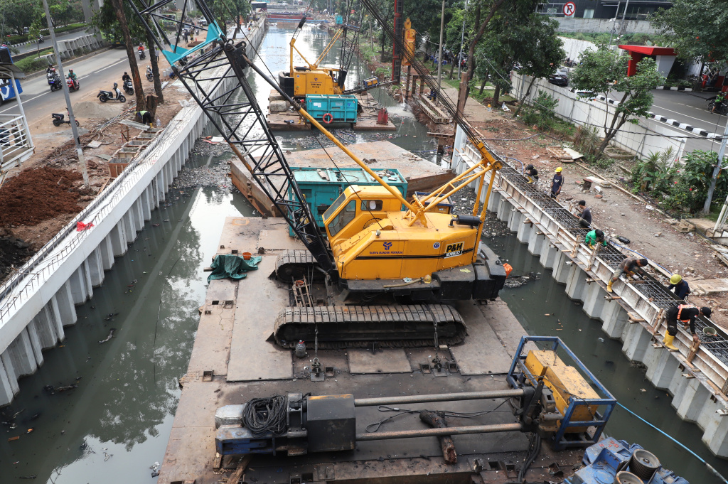 Pekerja sedang memasang rangka besi pada proyek pembangunan dinding turap Kali Cideng Atas, Jalan Rasuna Said (Ashar/SinPo.id)