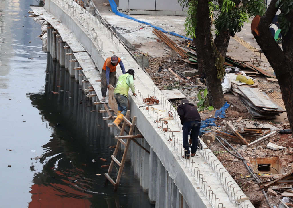 Pekerja sedang memasang rangka besi pada proyek pembangunan dinding turap Kali Cideng Atas, Jalan Rasuna Said (Ashar/SinPo.id)