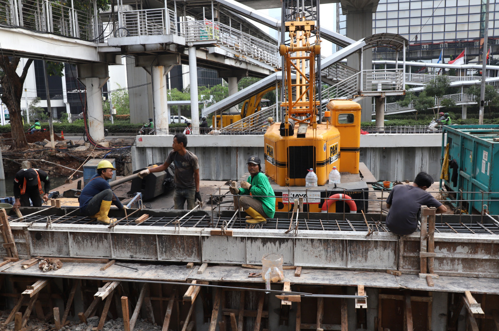 Pekerja sedang memasang rangka besi pada proyek pembangunan dinding turap Kali Cideng Atas, Jalan Rasuna Said (Ashar/SinPo.id)