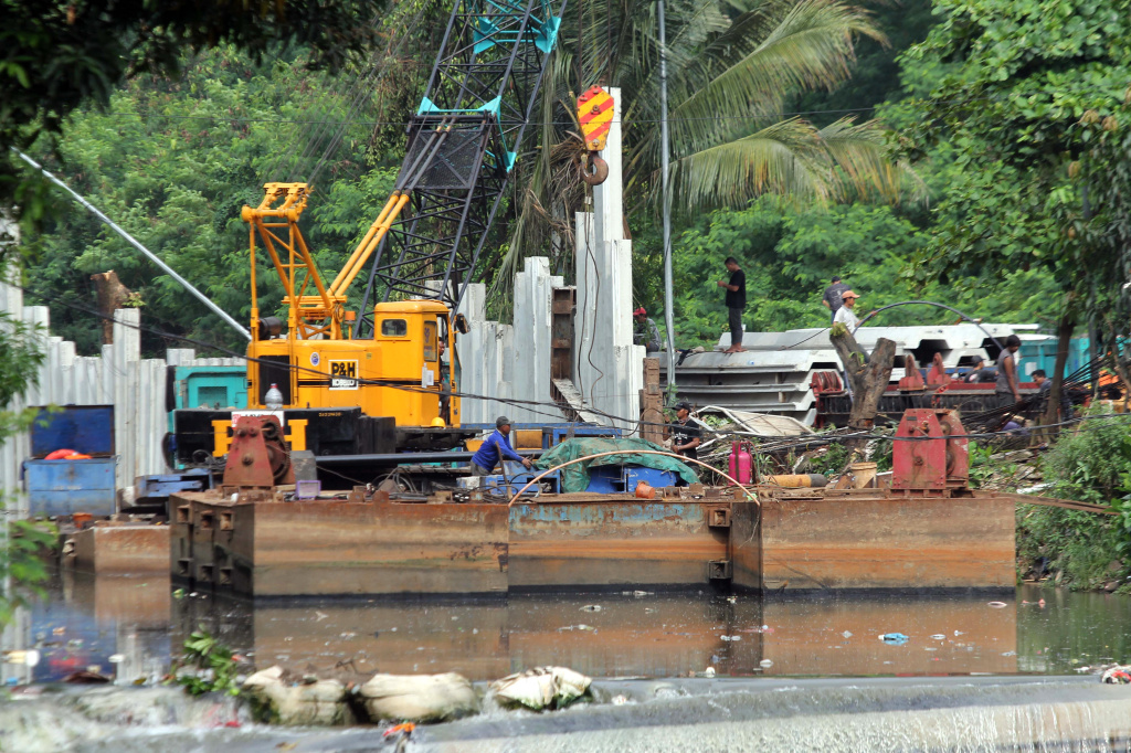 Pekerja sedang melakukan pengerukan lumpur di proyek revitalisasi kali Cideng (Ashar/SinPo.id)