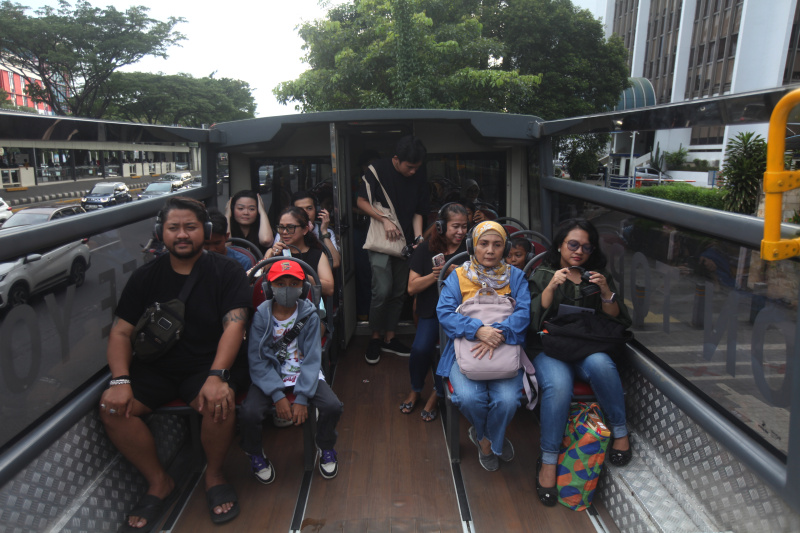 Wisatawan sedang menikmati layanan bus wisata Open Top Tour of Jakarta (Ashar/SinPo.id)