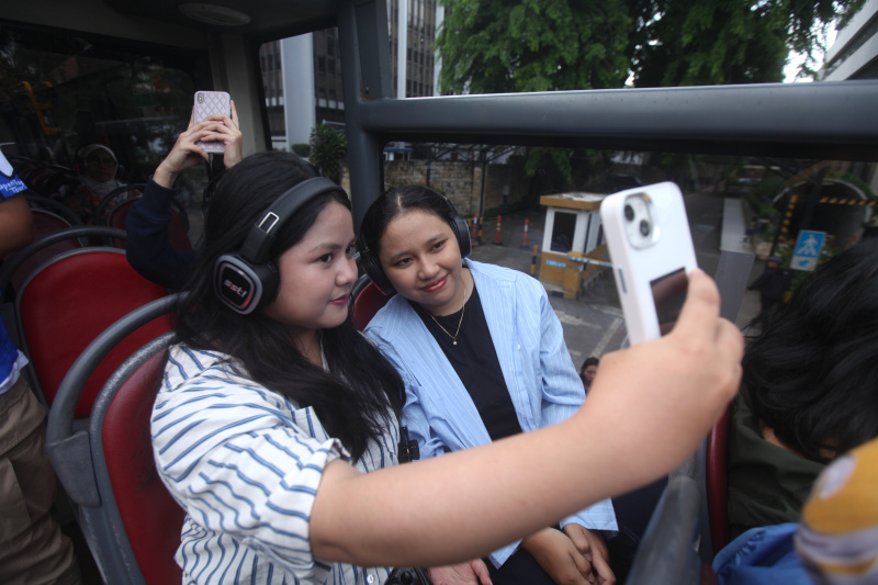 Wisatawan sedang menikmati layanan bus wisata Open Top Tour of Jakarta (Ashar/SinPo.id)