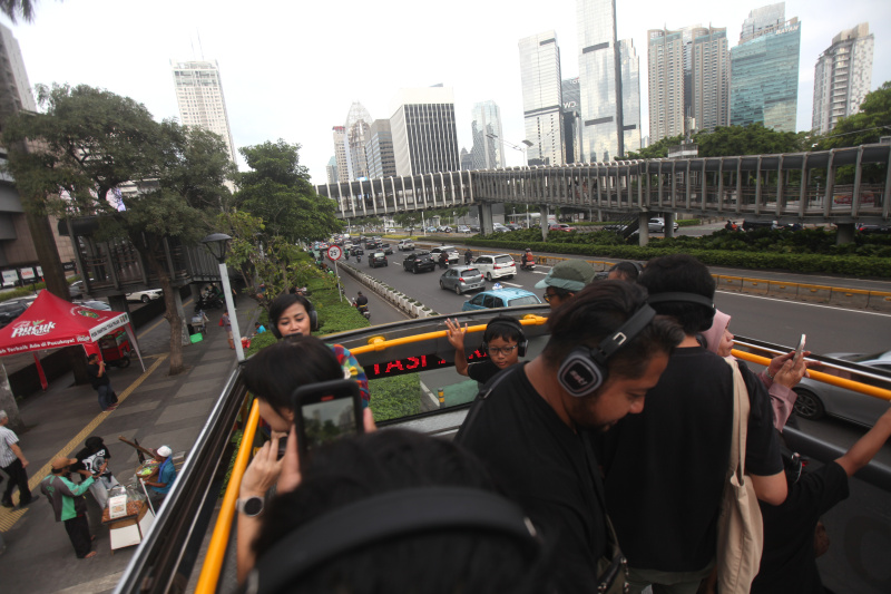 Wisatawan sedang menikmati layanan bus wisata Open Top Tour of Jakarta (Ashar/SinPo.id)