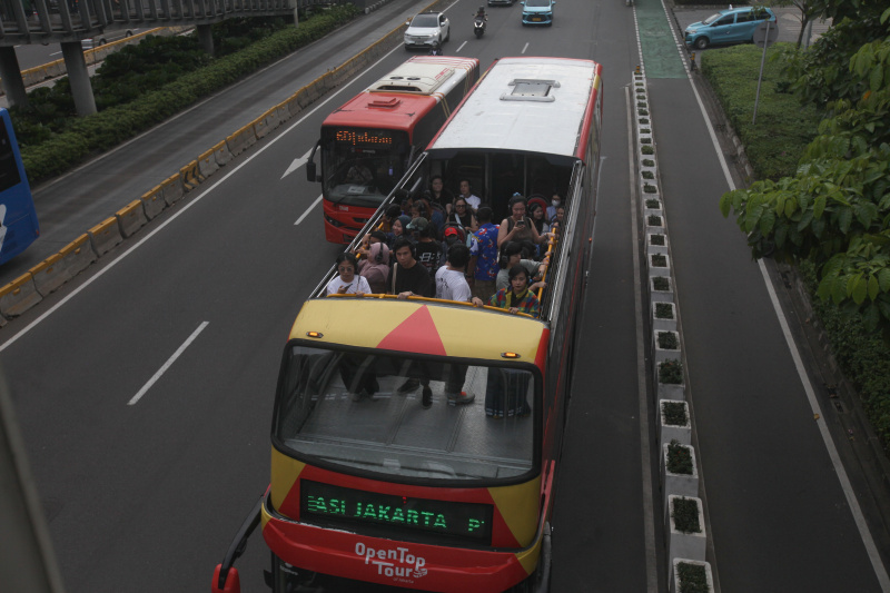 Wisatawan sedang menikmati layanan bus wisata Open Top Tour of Jakarta (Ashar/SinPo.id)