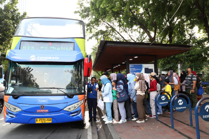 Warga mengantre untuk menaiki bus tingkat wisata atap terbuka Transjakarta di halte Irti Monas (Ashar/SinPo.id)