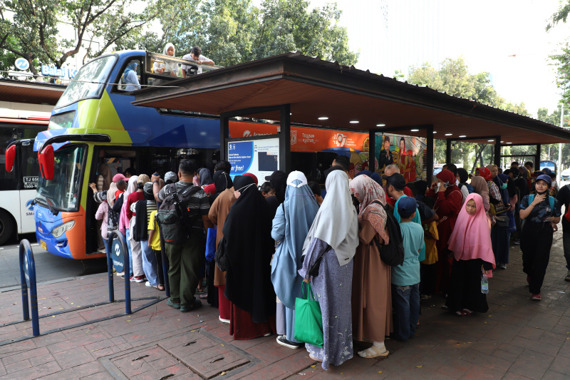 Warga mengantre untuk menaiki bus tingkat wisata atap terbuka Transjakarta di halte Irti Monas (Ashar/SinPo.id)