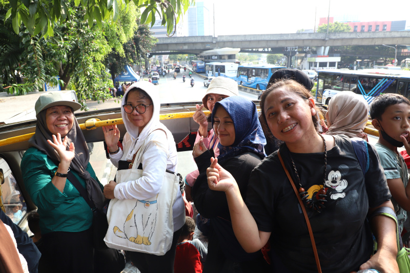 Warga mengantre untuk menaiki bus tingkat wisata atap terbuka Transjakarta di halte Irti Monas (Ashar/SinPo.id)