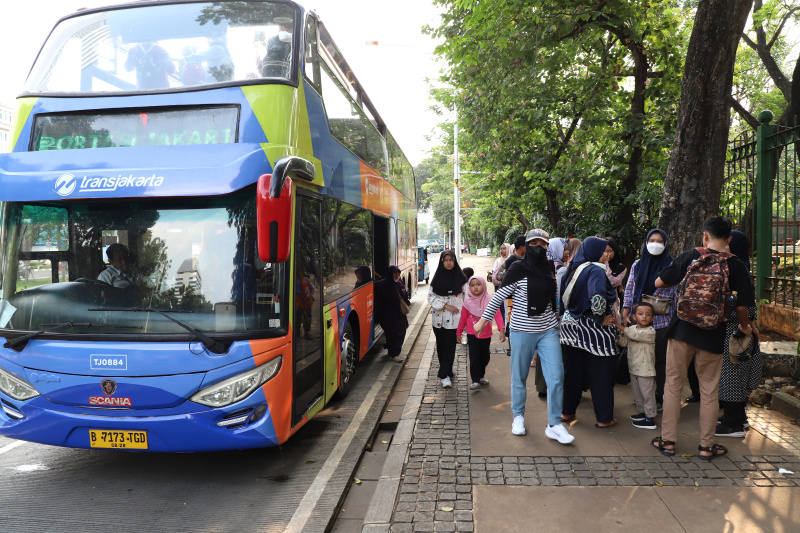 Warga mengantre untuk menaiki bus tingkat wisata atap terbuka Transjakarta di halte Irti Monas (Ashar/SinPo.id)