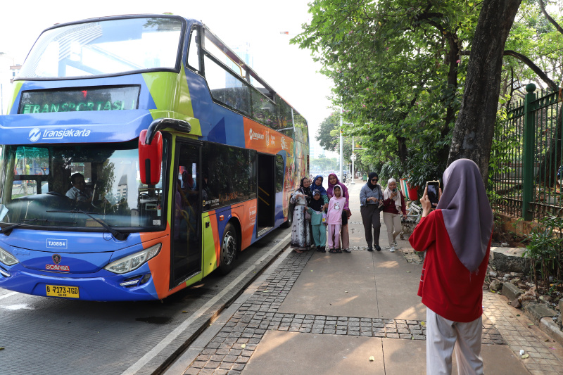 Warga mengantre untuk menaiki bus tingkat wisata atap terbuka Transjakarta di halte Irti Monas (Ashar/SinPo.id)