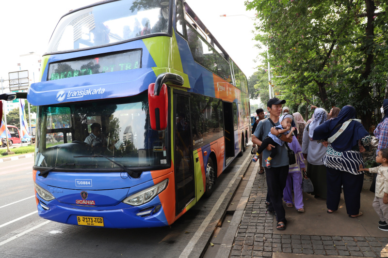 Warga mengantre untuk menaiki bus tingkat wisata atap terbuka Transjakarta di halte Irti Monas (Ashar/SinPo.id)