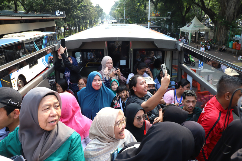 Warga mengantre untuk menaiki bus tingkat wisata atap terbuka Transjakarta di halte Irti Monas (Ashar/SinPo.id)