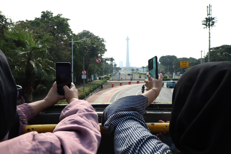 Warga mengantre untuk menaiki bus tingkat wisata atap terbuka Transjakarta di halte Irti Monas (Ashar/SinPo.id)