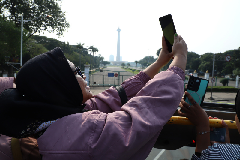 Warga mengantre untuk menaiki bus tingkat wisata atap terbuka Transjakarta di halte Irti Monas (Ashar/SinPo.id)