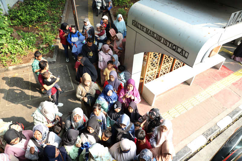 Warga mengantre untuk menaiki bus tingkat wisata atap terbuka Transjakarta di halte Irti Monas (Ashar/SinPo.id)